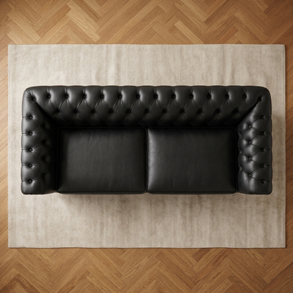 Sofá Chesterfield Preto Grafite de 2 lugares visto de cima, sobre tapete claro e piso espinha de peixe