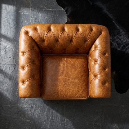 Poltrona Chesterfield Caramelo vista de cima sobre fundo de pedra escura, destacando o cravejado de tachas
