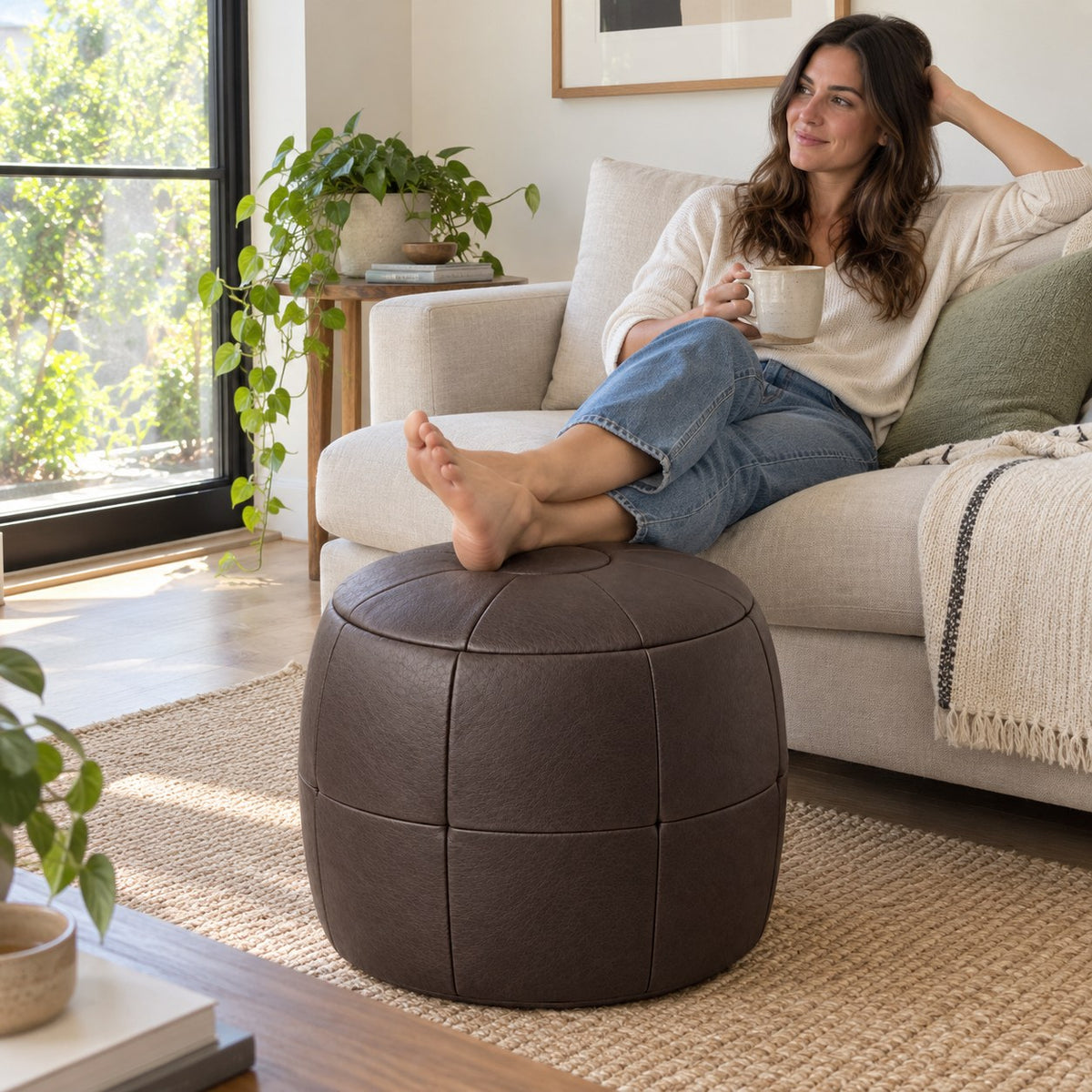 Puff Pipa Café em Couro Natural Premium 40x40cm — lifestyle com pessoa usando o puff em ambiente residencial claro