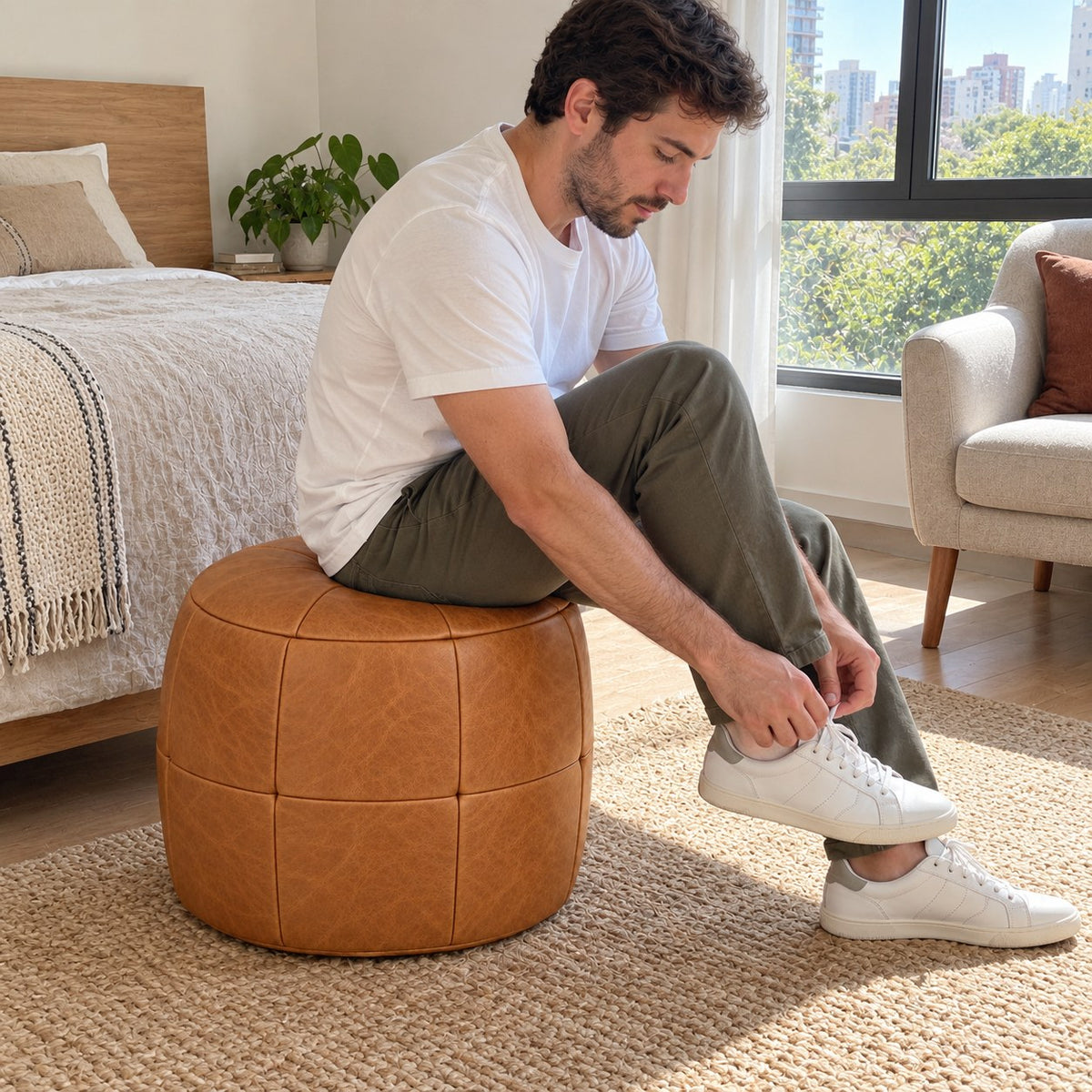 Puff Pipa Caramelo em Couro Natural Premium 40x40cm — lifestyle com pessoa usando o puff em ambiente residencial claro