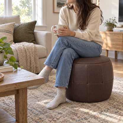 Puff Pipa Café em couro natural premium — Pessoa sentada no puff em sala clara