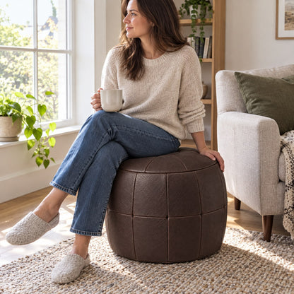 Puff Pipa Café em couro natural premium — Pessoa usando o puff junto à poltrona
