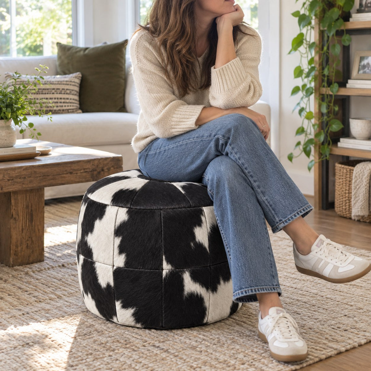 Puff Pipa Malhado Preto e Branco em couro natural premium — Pessoa sentada no puff em sala clara