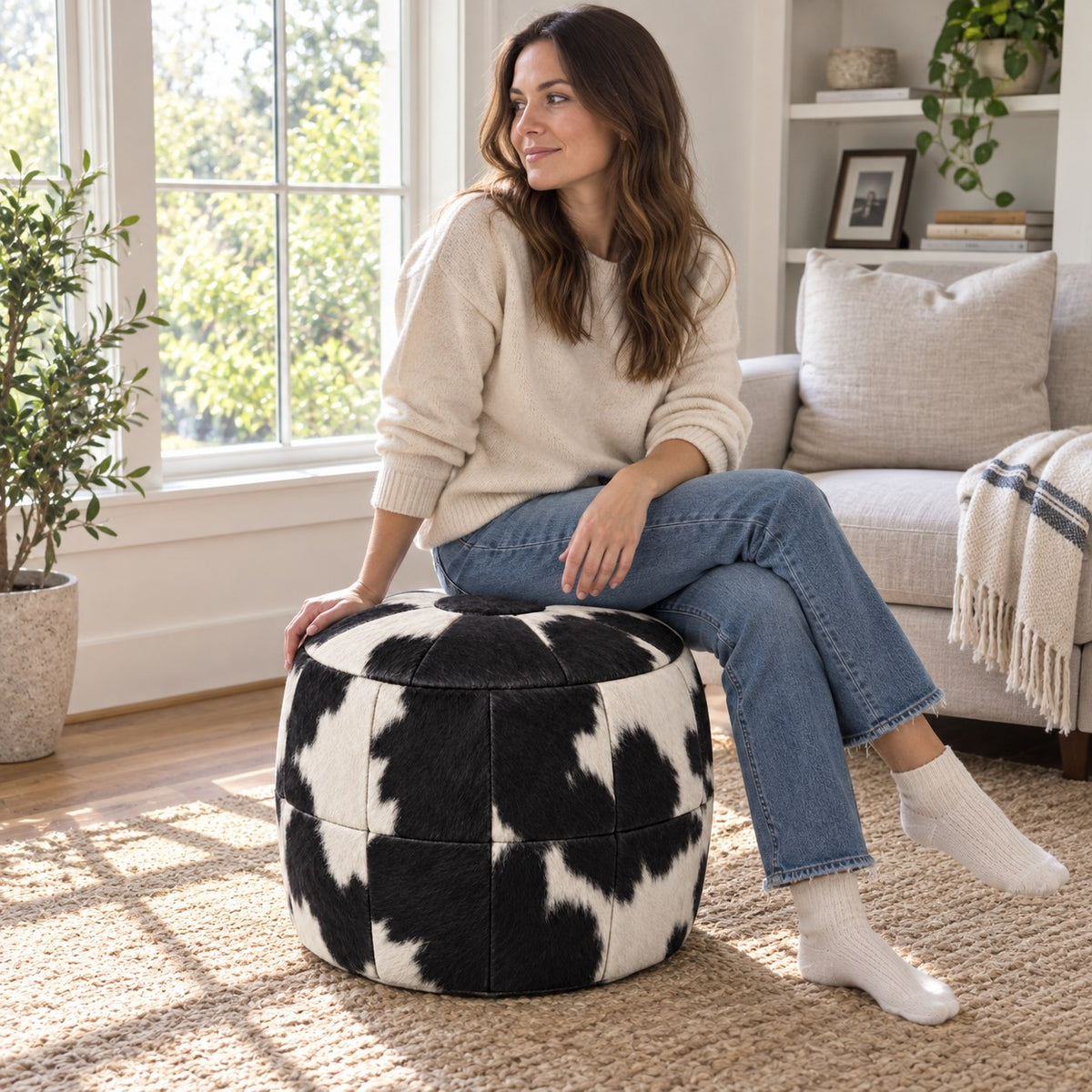 Puff Pipa Malhado Preto e Branco em couro natural premium — Pessoa usando o puff junto à poltrona