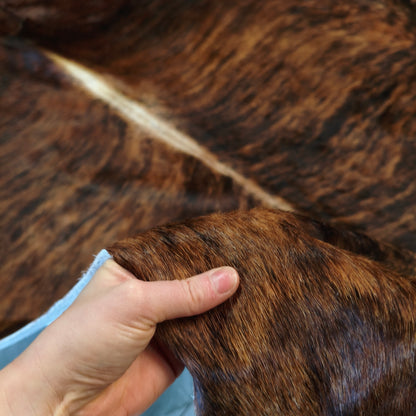 Mão levantando a borda do tapete BZE1313 para mostrar o pelo curto